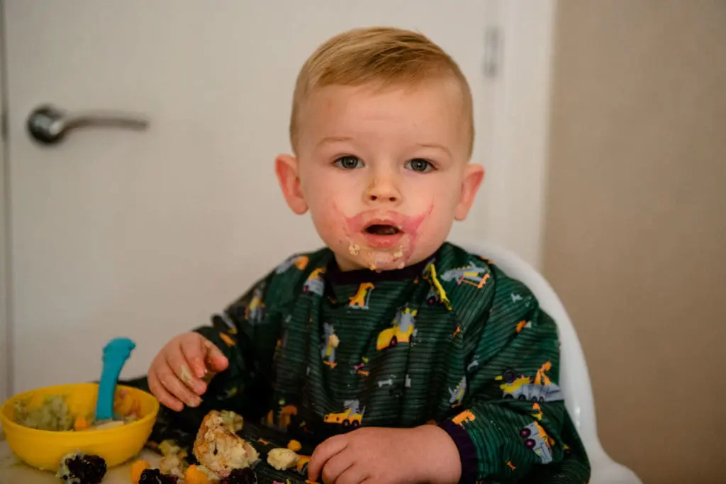 Family portfolios - a little boy sits in his highchair with food all over his face!