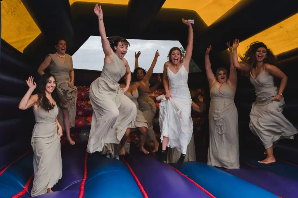 Hiring a professional wedding photographer - a bride and her bridesmaids are jumping on a bouncy castle