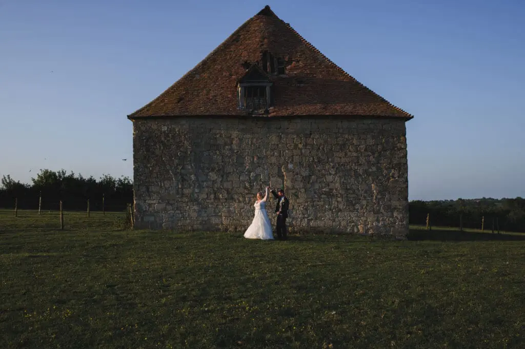 Bedford wedding photographer - a bridal couple are in a field dancing in front of a large barn