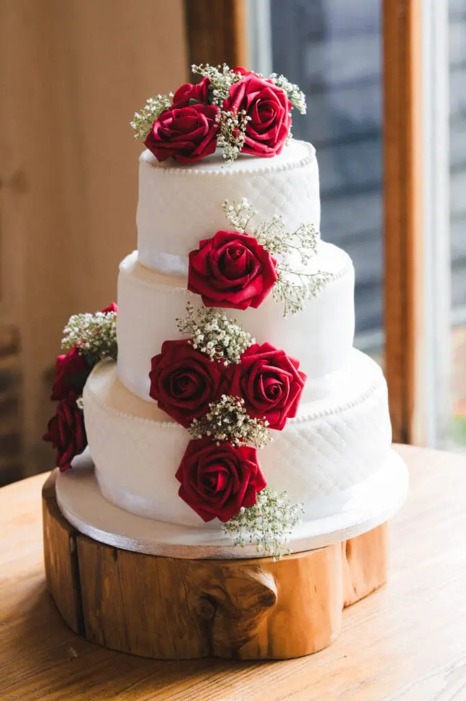 Winter Wedding Floral Trends, deep red fresh flowers on a 3-tier white wedding cake