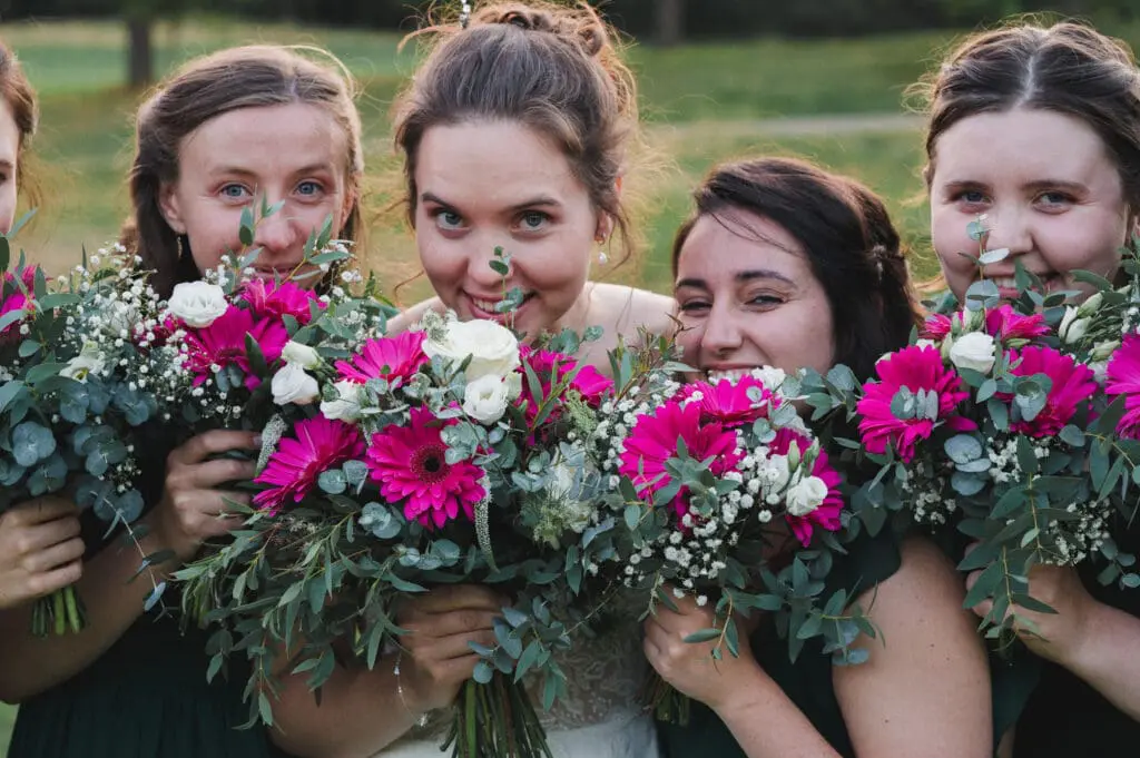 Look natural in your wedding photos like this bride and bridesmaids peeping over their bouquets