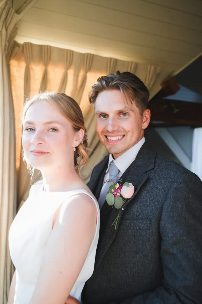Close up of a Bride and groom standing side on to the camera and turning to smile at it