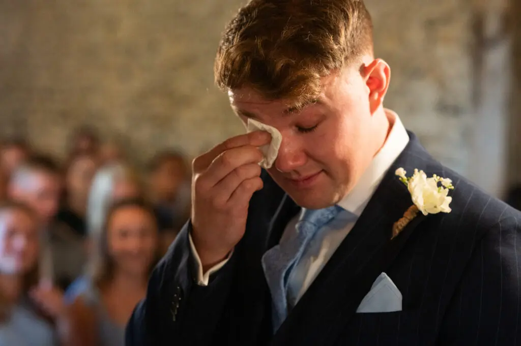 UK wedding photography trends capturing real emotion, like this groom who is wiping tears from his eyes