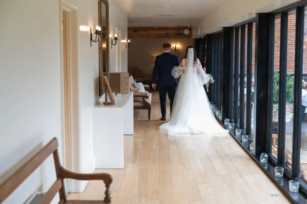 professional wedding vendors like granary estates where this bride and groom are walking away from the camera with full length windows to their right