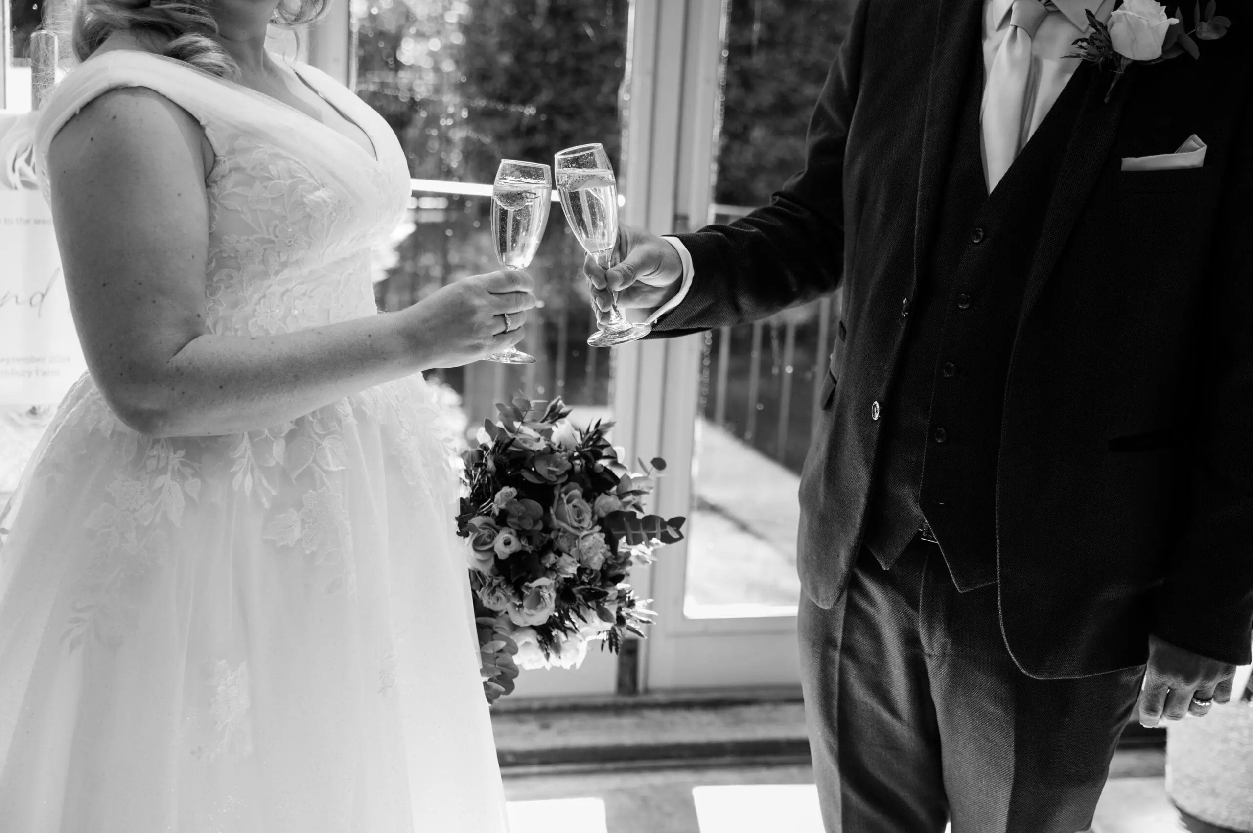 B&W image of newly married couple toasting champagne