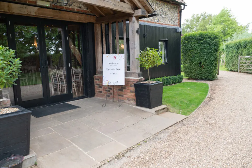 Outside the Granary Estates wedding venue, with a sign for Faye and Luke's wedding on an easel.