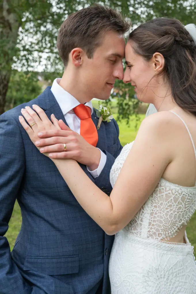 A candid wedding photography style image of a bride and groom sharing an intimate moment as their heads and noses touch