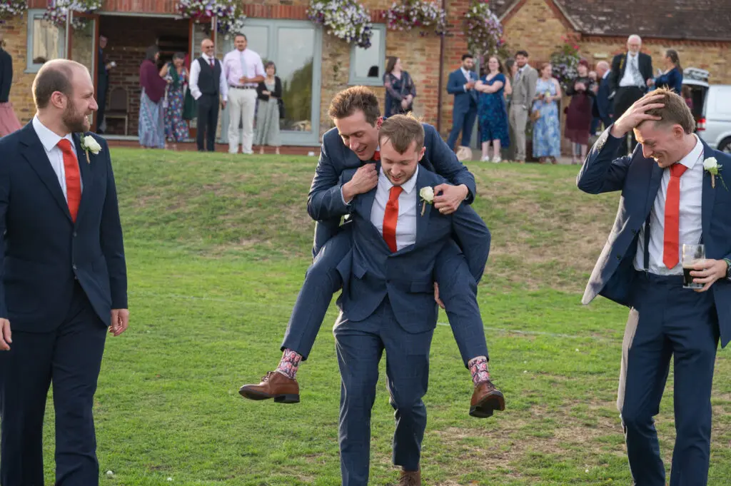 Eversholt Hall weddings a groom and his 4 groomsmen - the groom is having a piggyback with his best man
