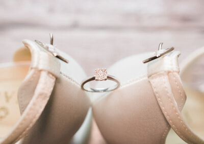 wedding photographer in Bedfordshire - a close up of the back of cream bridal shoes with her engagement ring balancing between them