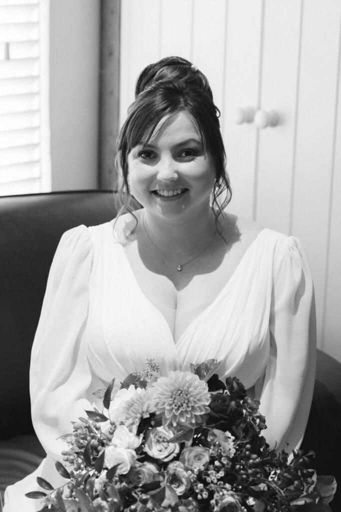 Sheene Mill Weddings in Cambridgeshire - B&W close up of a smiling bride holding her bouquet