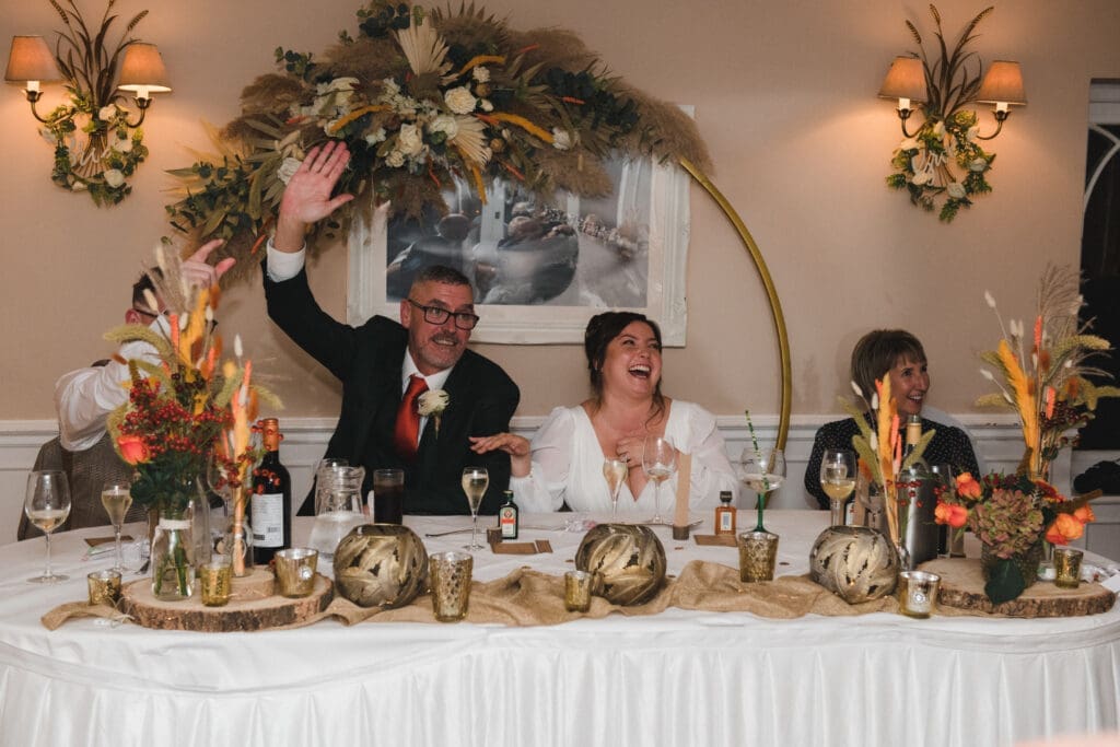 Sheene Mill Weddings in Cambridgeshire - Newly married couple cheering at the top table during the wedding breakfast