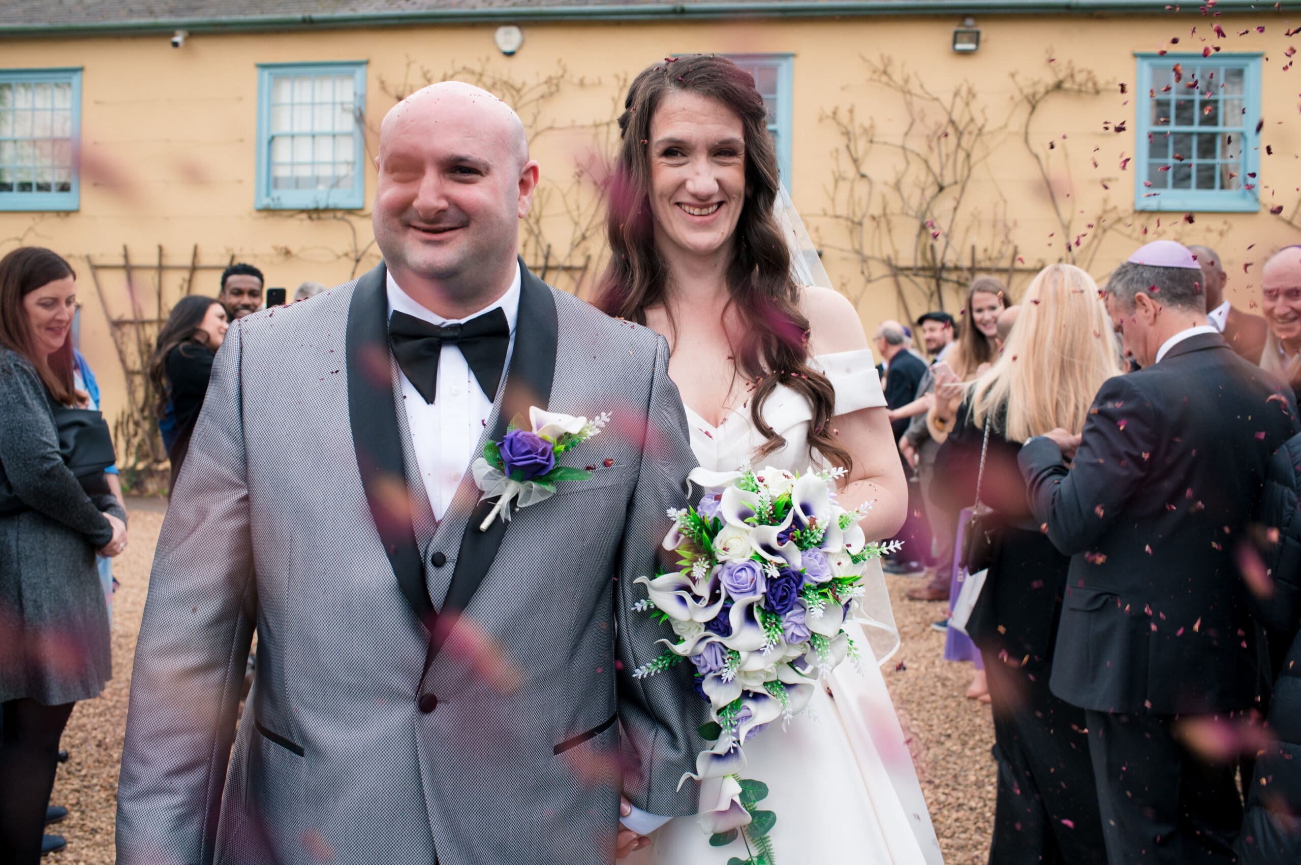 Just married couple with guests throwing confetti