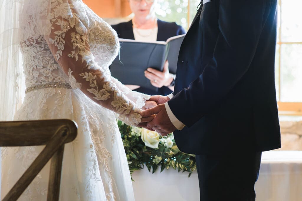 Buckinghamshire's Notely Tythe Barn - close up of Bride and Groom's hands, holding each other during the ceremony