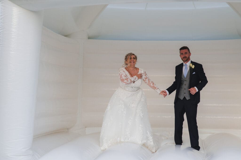 Buckinghamshire's Notely Tythe Barn - Bride and Groom on a white Bouncy Castle