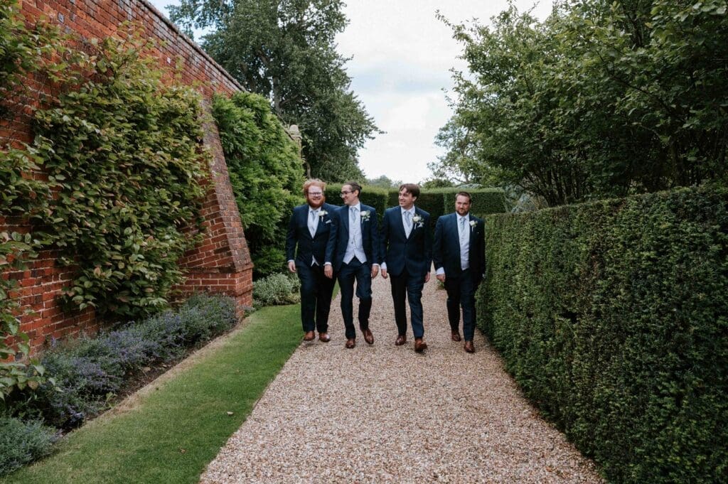 Braxted Park Wedding Photographer - The Groom and his Groomsmen walking through the walled garden