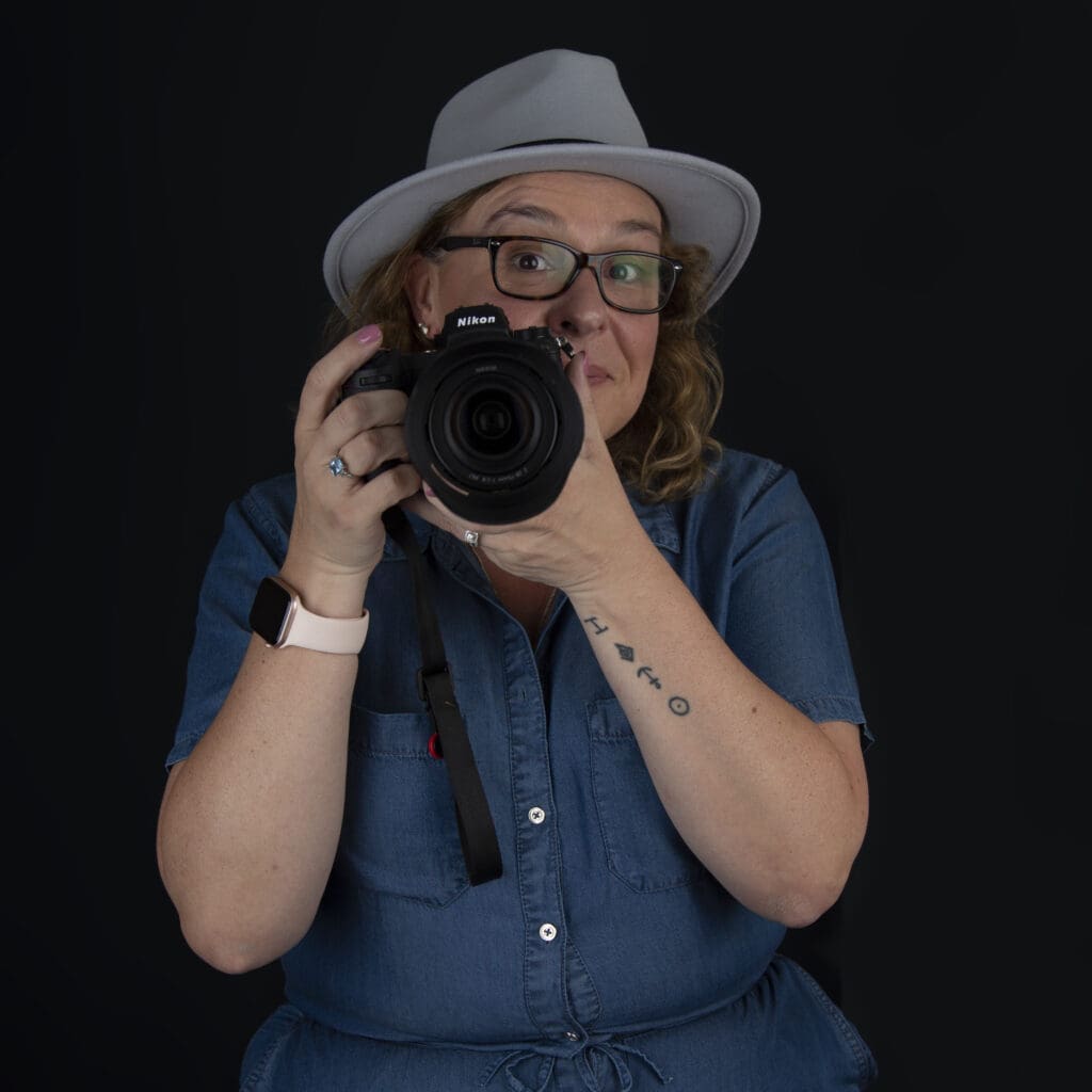 Catherine Brooks wearing a hat and holding a camera while being a wedding photographer
