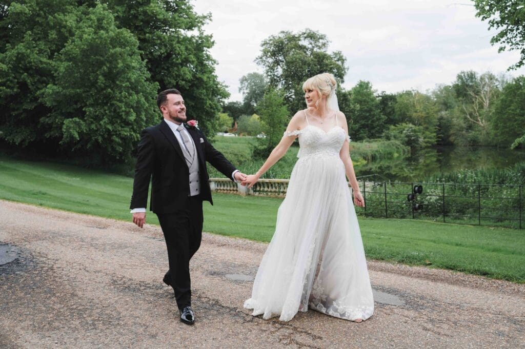 Bride & Groom walking over the bridge at Braxted Park wedding venue