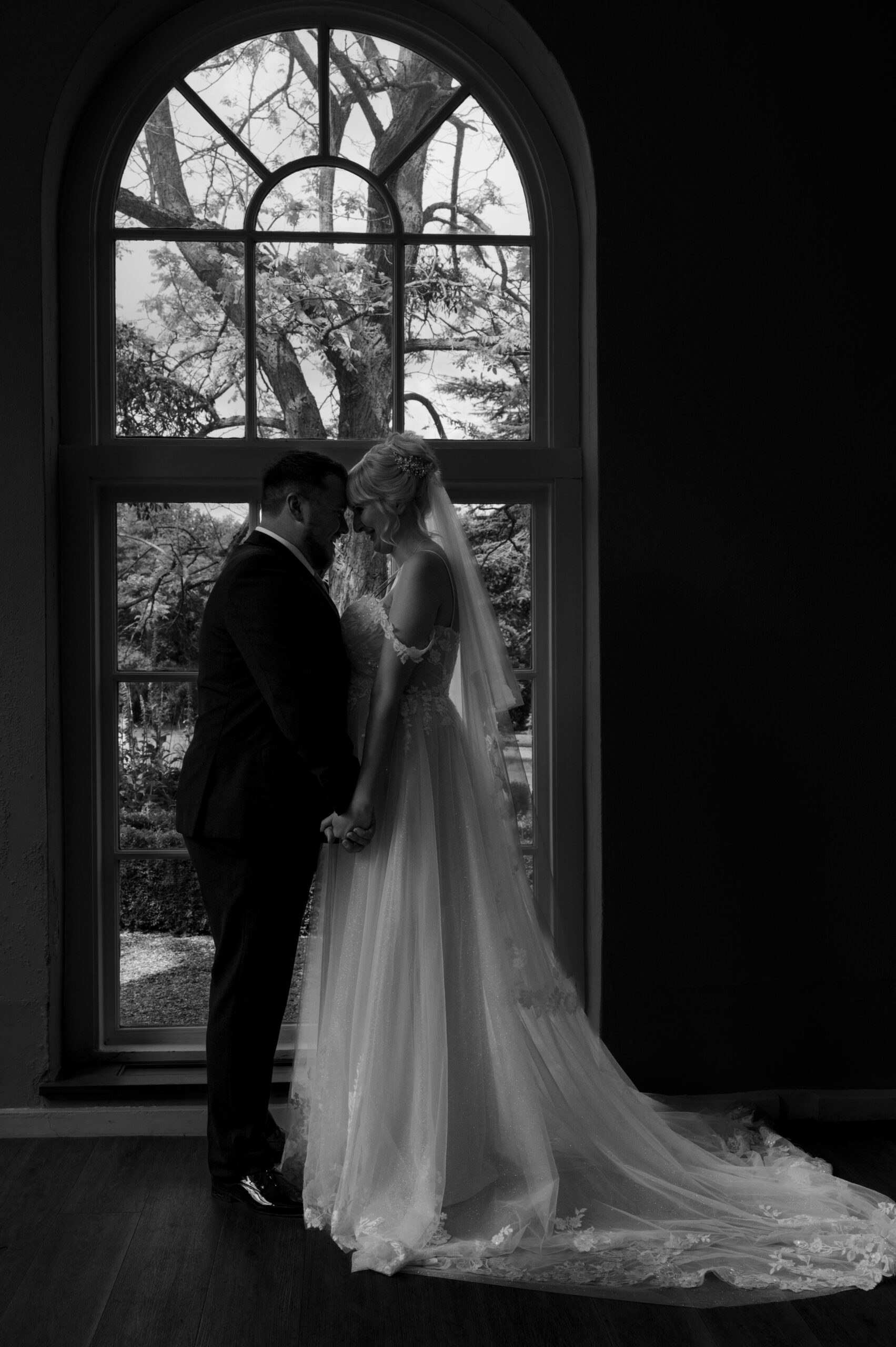 Wedding Photographer In Bedfordshire - Newly married couple in front of the window in the Orangery at Braxted Park