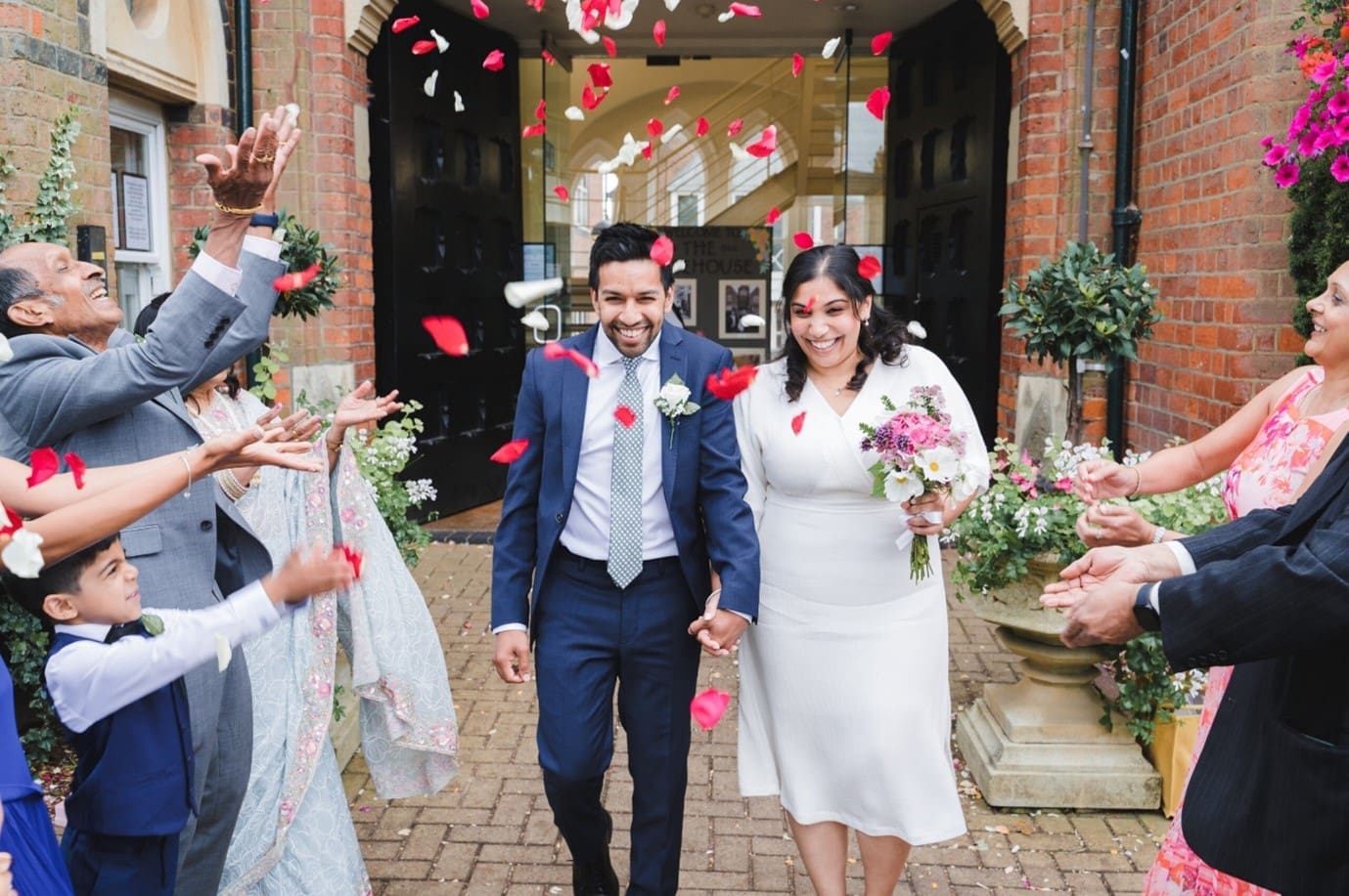 Wedding Photography Prices - A bride and groom walk between their guests in a shower of confetti