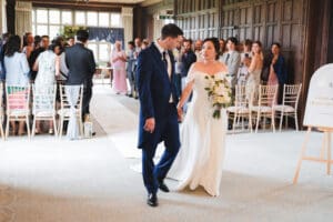 Candid Wedding Photography - a couple are holding hands, looking at each other as they leave the ceremony