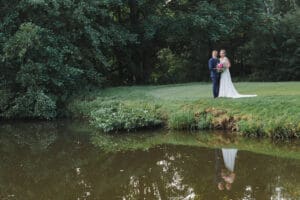 Hiring a Professional wedding photographer - a bridal couple stand centre right with trees behind them and a lake in the foregound