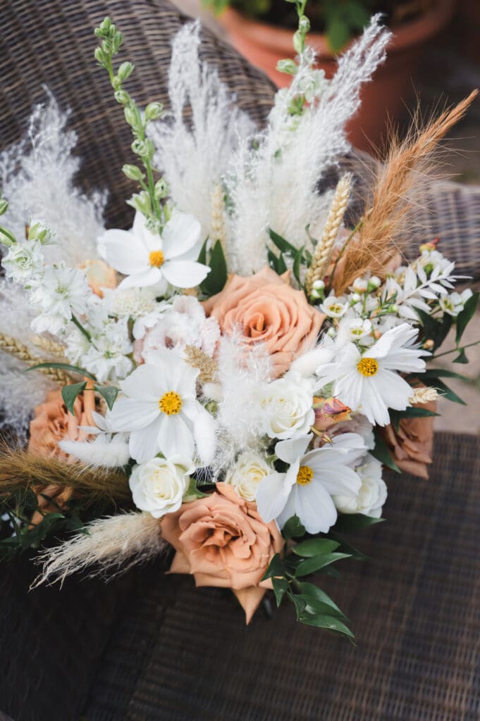 Weddings in Bedfordshire a natural bouquet of peach roses, delicate white flowers and fronds of wheat and fluffy seed stems