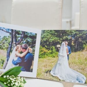 wedding album investment - an open album showing a wedding image per page, a sprig of lily of the valley is on the chair in the corner
