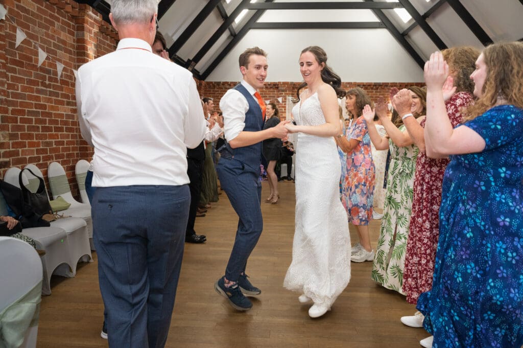 Eversholt Hall Weddings - the bride and groom skipping hand in hand through lines of guests clapping.